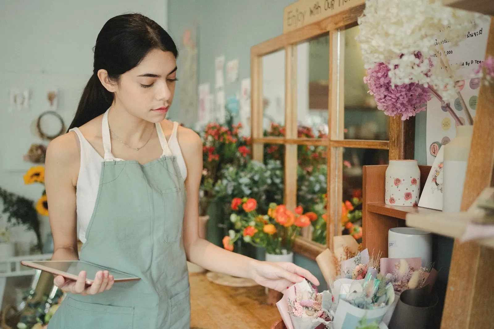 A florist checking orders on a tablet in her flower shop
